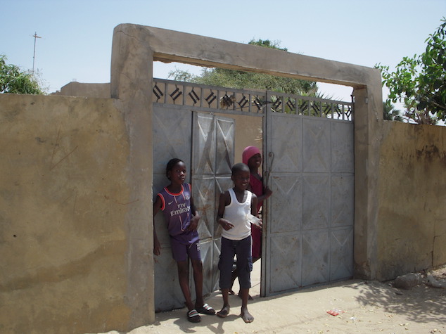 Image of 3 kids standing by the door of their house